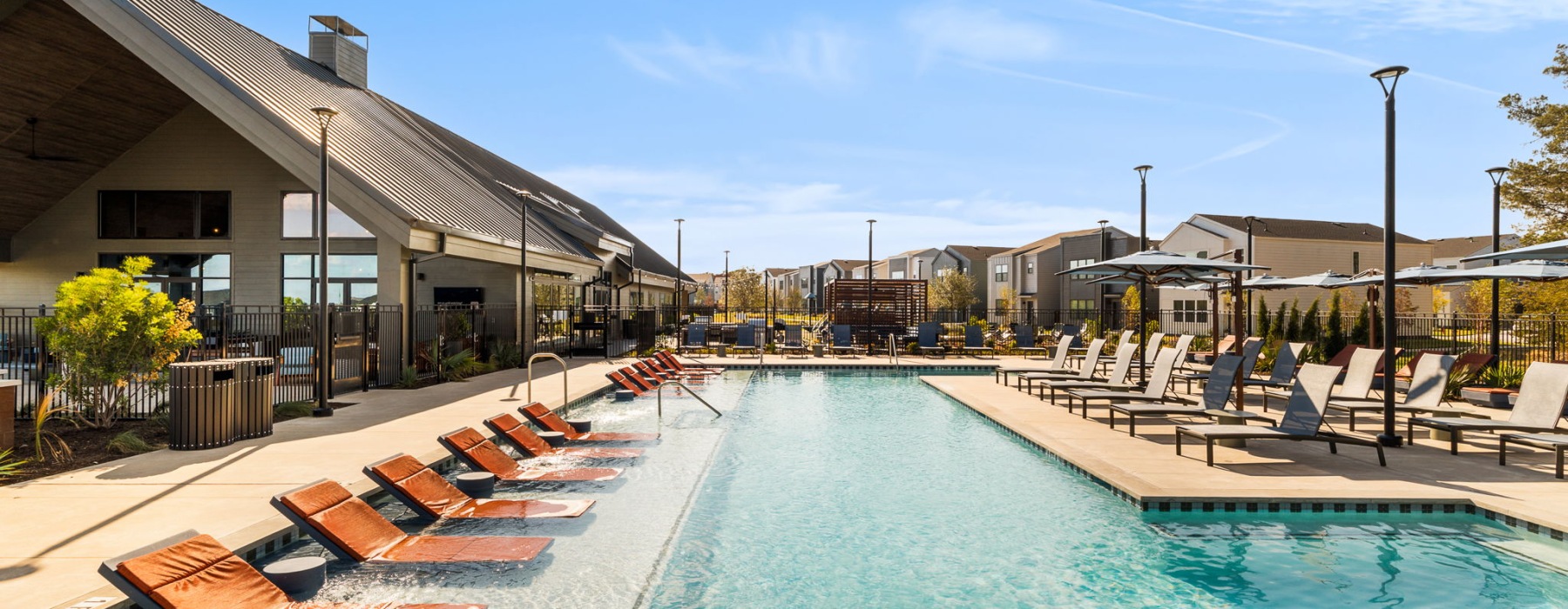 a large pool with lounge chairs next to an amenity clubhouse