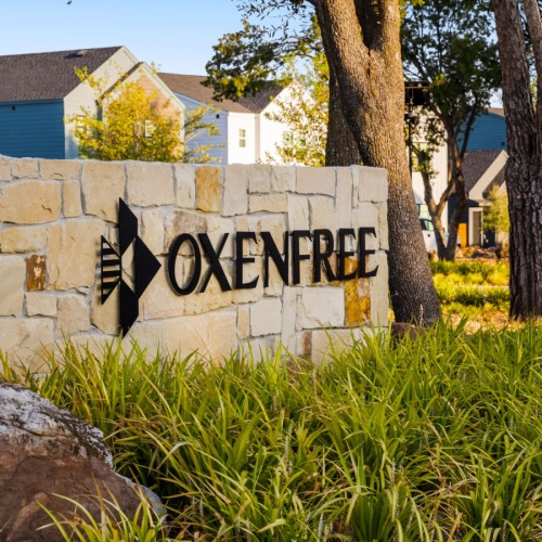 a monument sign framed by plans and trees