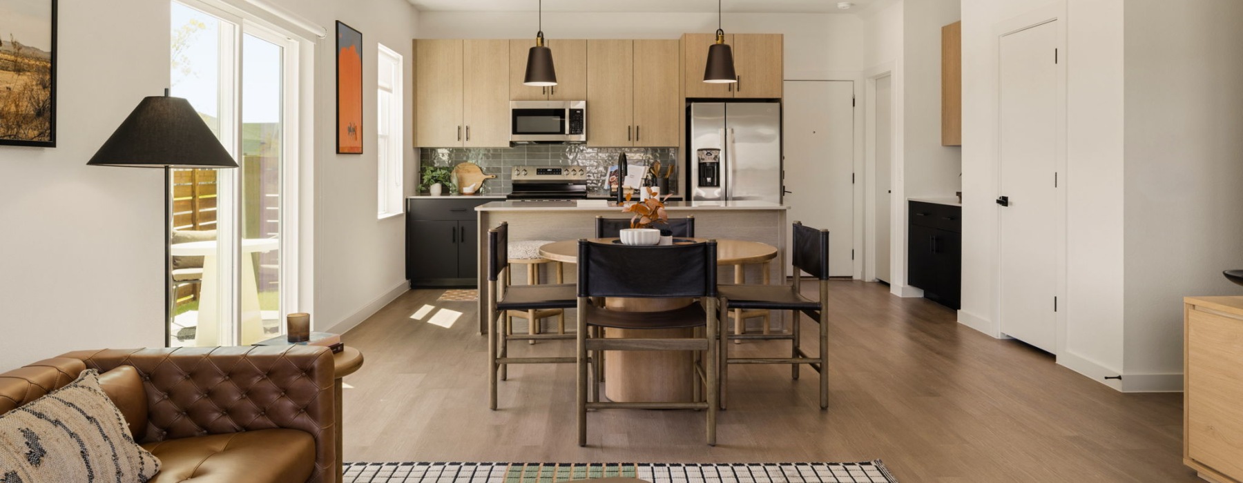an open kitchen and living room of a rental townhome with wood floors