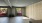 a room with a large window, a mirror and wood paneling on the wall