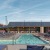 a swimming pool with chairs and a building in the background