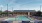a swimming pool with chairs and a building in the background